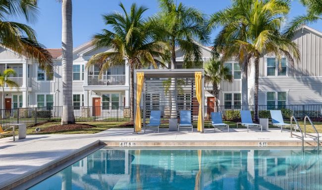 a swimming pool with palm trees and a building in the background