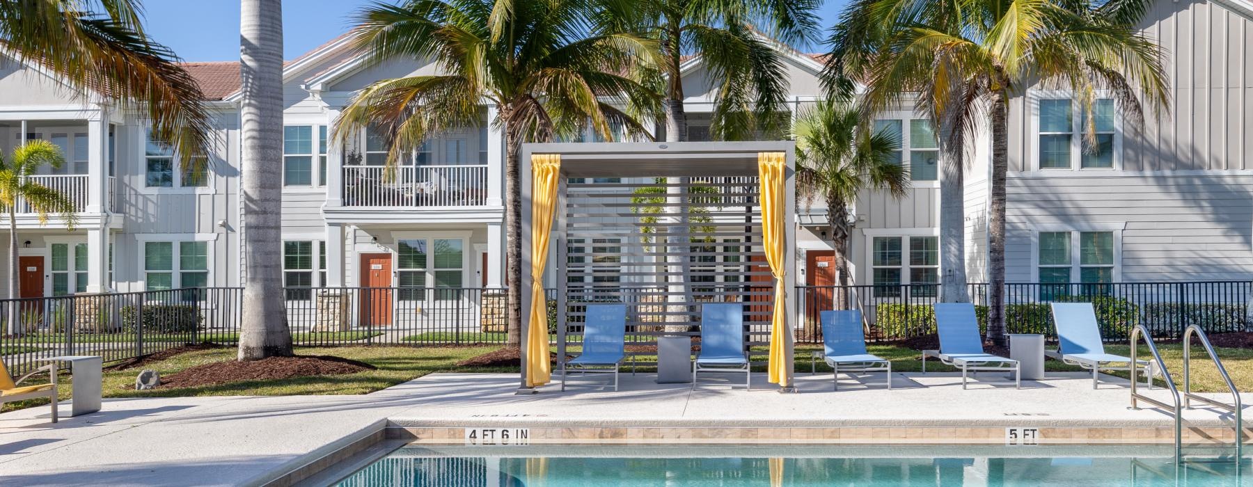 a swimming pool with palm trees and a building in the background